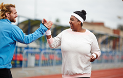 Male personal trainer high fiving woman on outdoor track